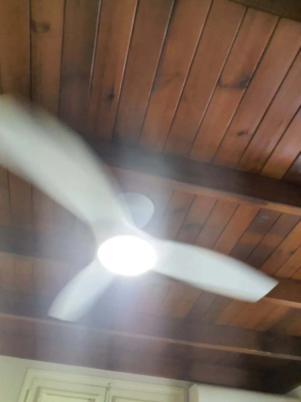 Brasseur d'air FANELITE blanc posé sous un lambris de bois verni au Vauclin